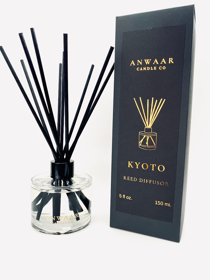 A black reed diffuser with clear glass and black sticks, and a black packaging box with 'ANWAAR' and 'KYOTO' text, indicating the fragrance story and brand.