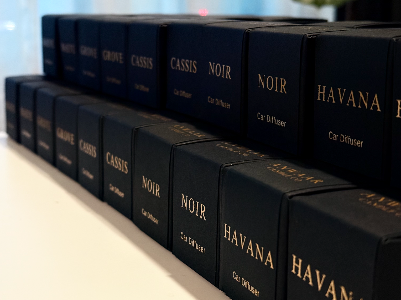 row of car diffuser black square boxes with gold scent description on each 