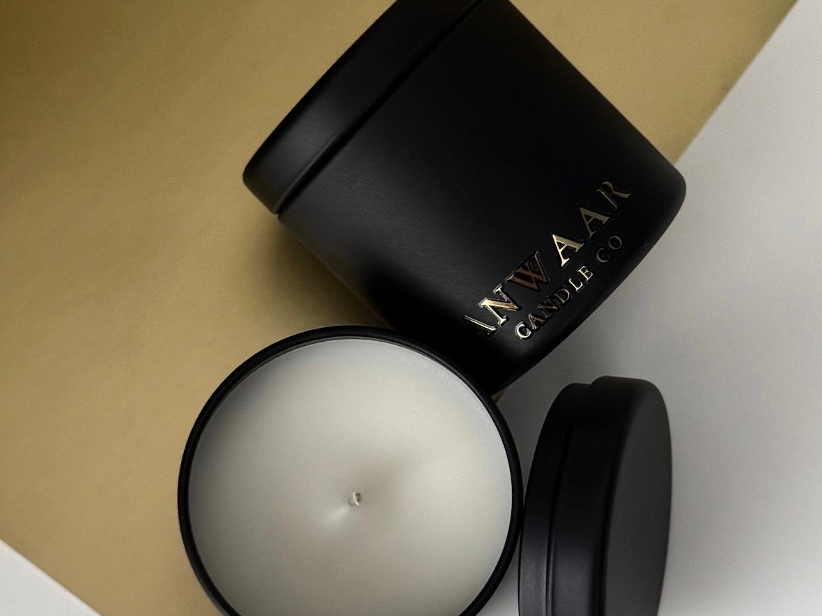 Black candle jar with lid on a beige surface