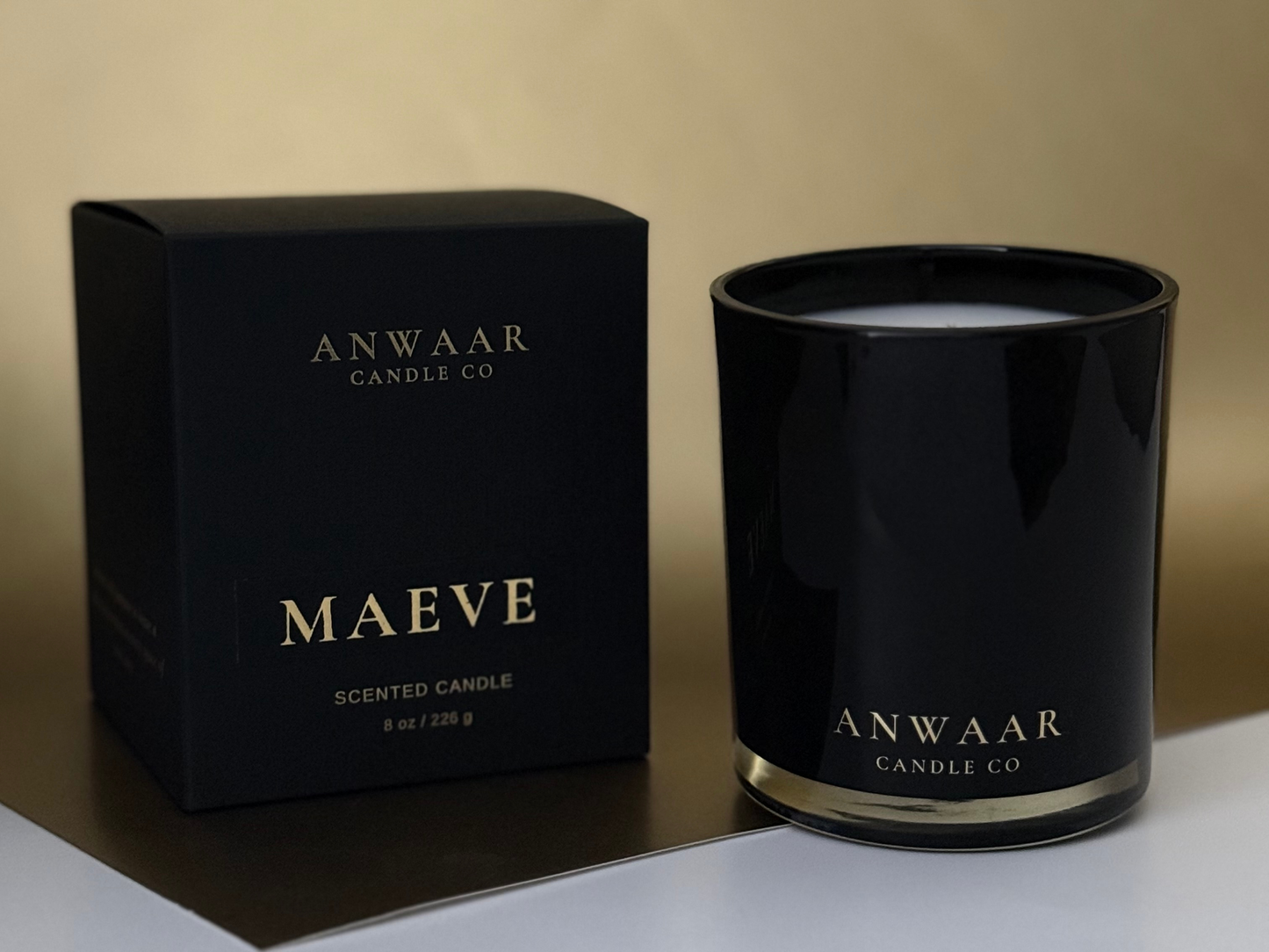 Black candle and packaging with 'Anwaar Candle Co' branding on a neutral background